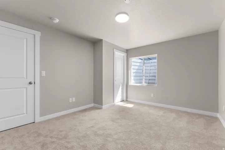 Unfurnished bedroom featuring light colored carpet and baseboards