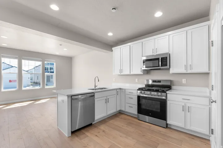 Kitchen featuring stainless steel appliances, white cabinets, light wood-style flooring, a peninsula, and recessed lighting