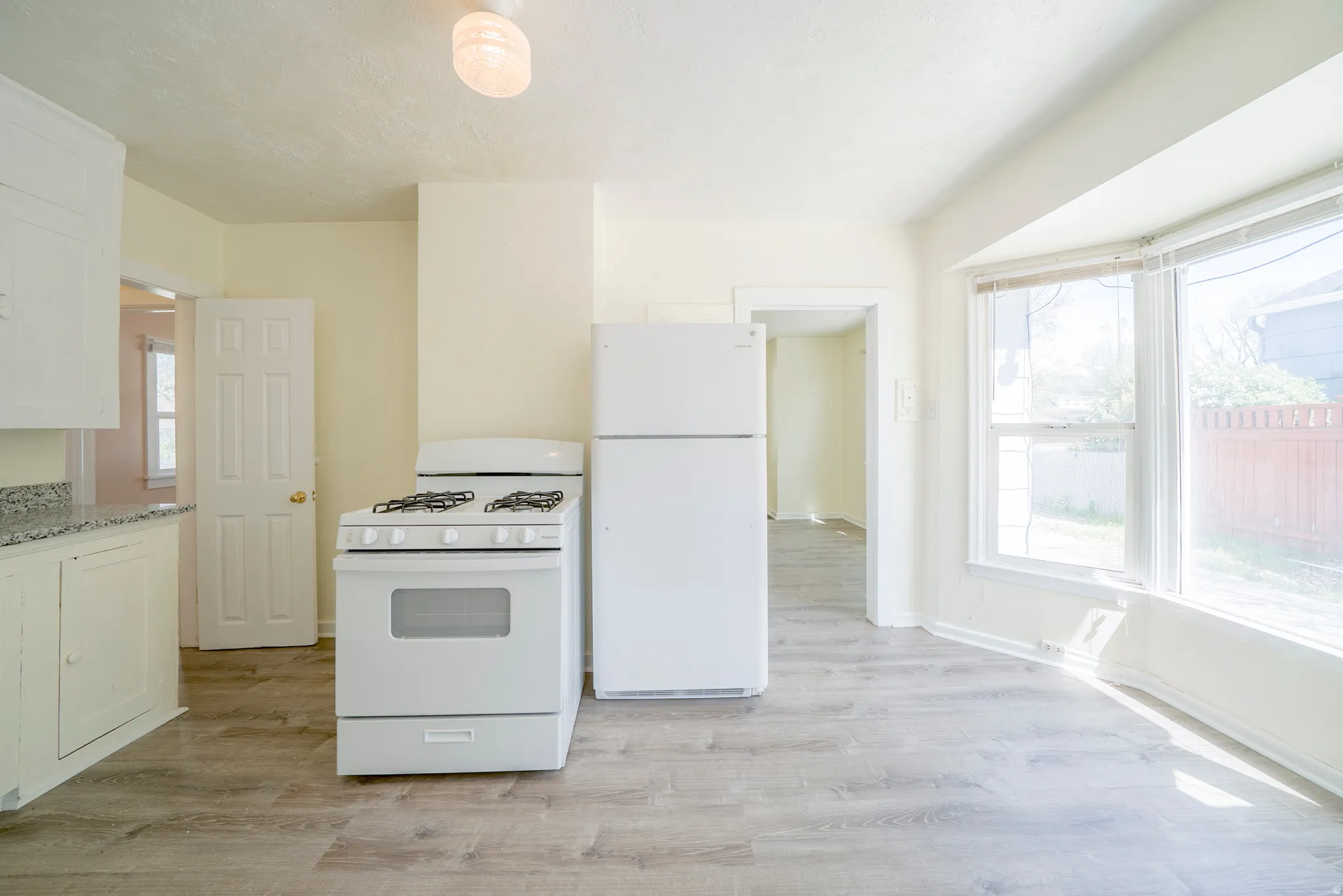Kitchen with white appliances, light wood finished floors, and white cabinets