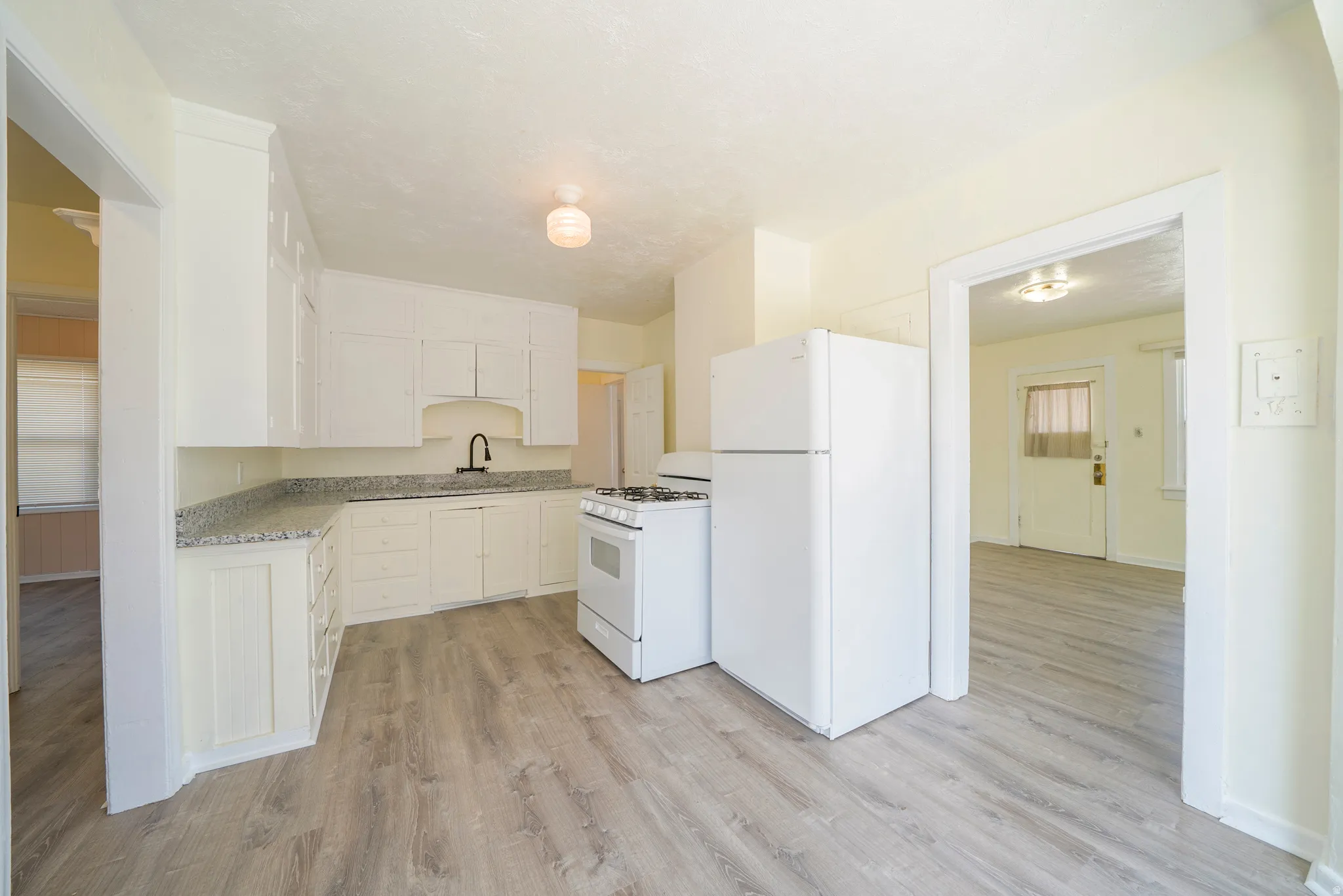 Kitchen featuring white appliances, light wood-style flooring, and white cabinets