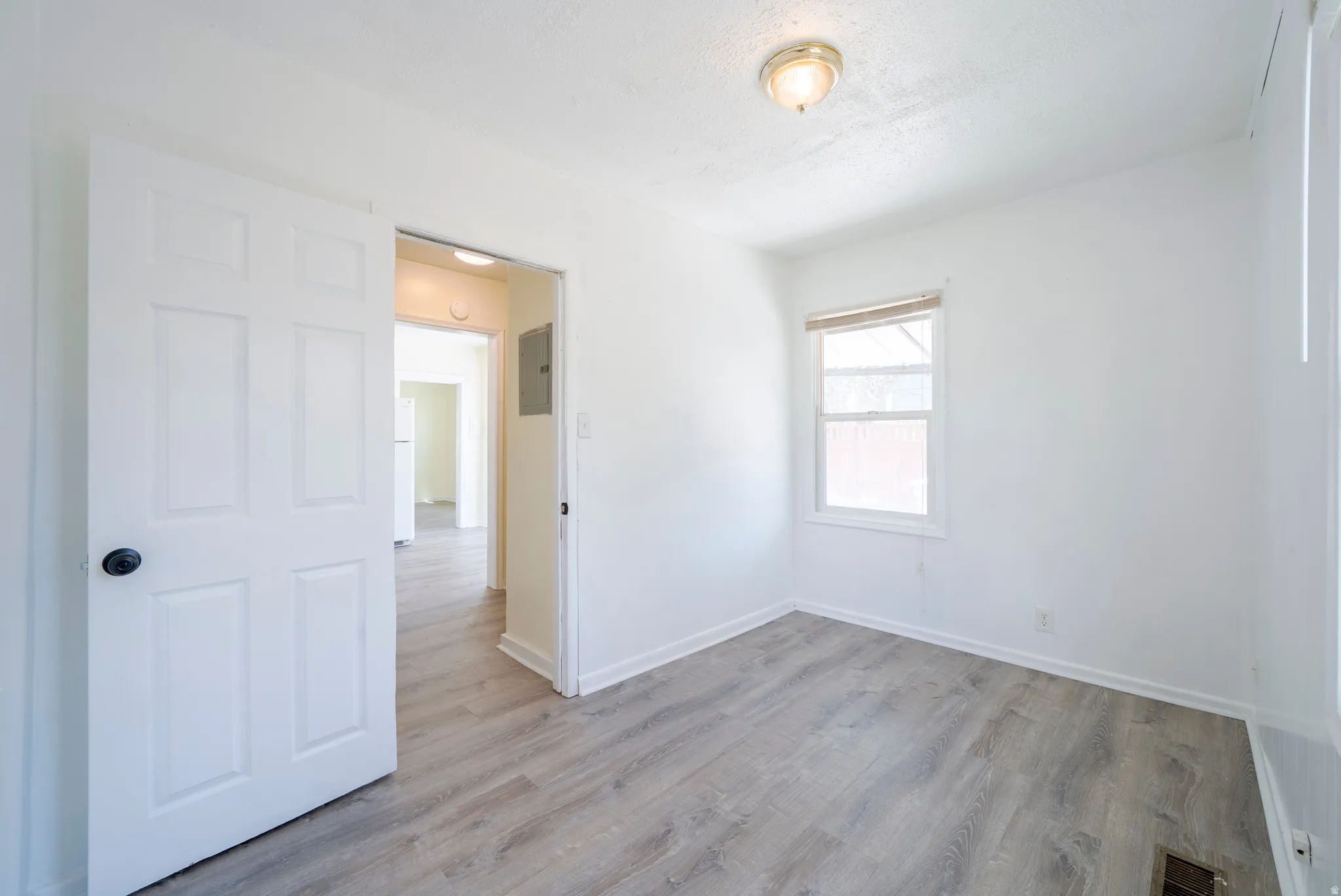 Unfurnished room featuring light wood finished floors and a textured ceiling