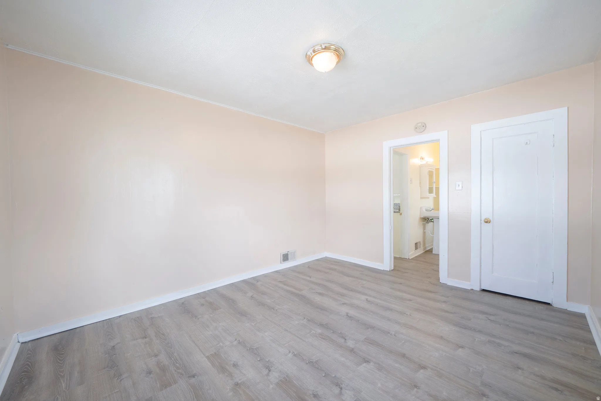 Unfurnished bedroom with light wood finished floors and ensuite bathroom