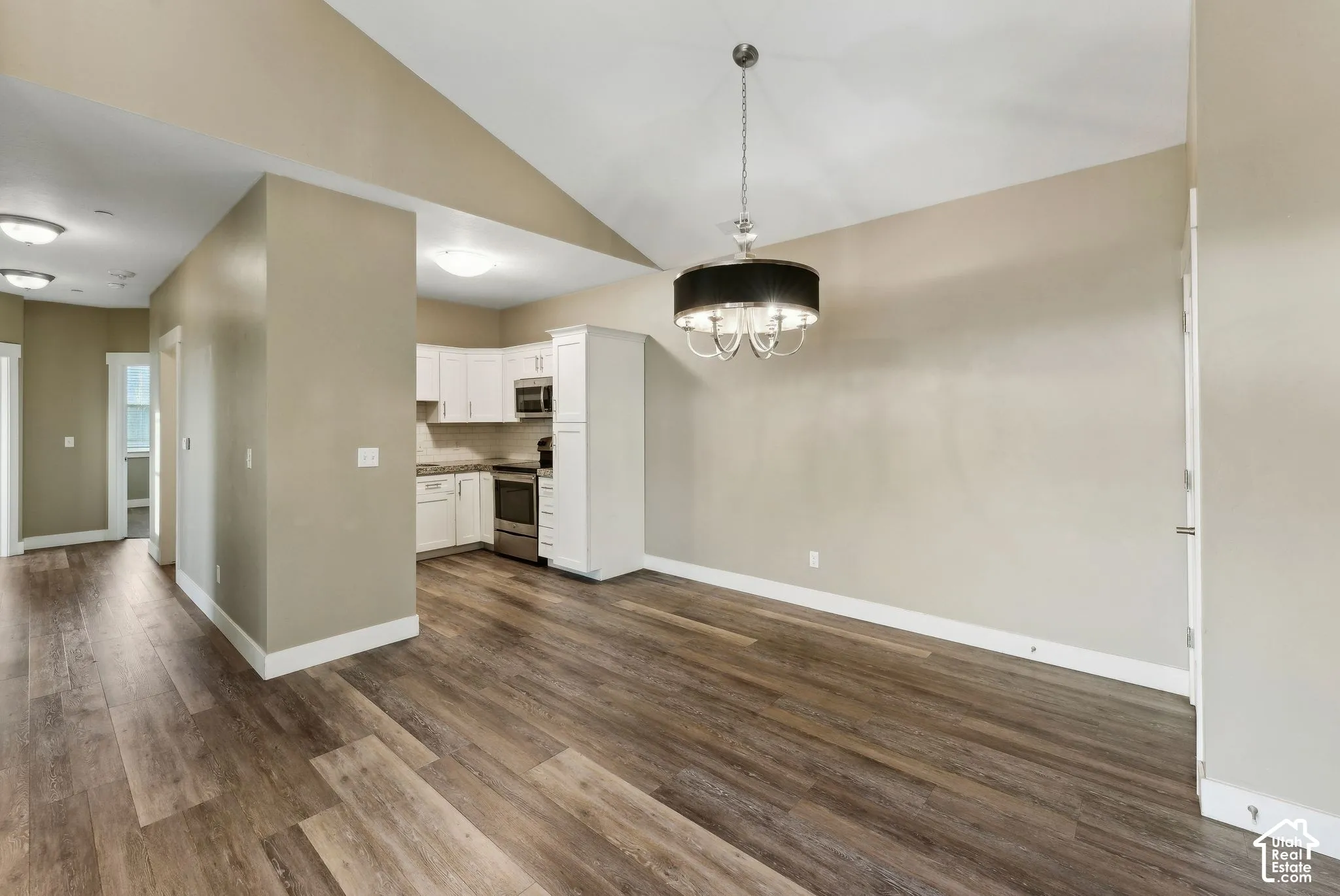 Unfurnished dining area with lofted ceiling, dark wood-type flooring, and suspended lighting
