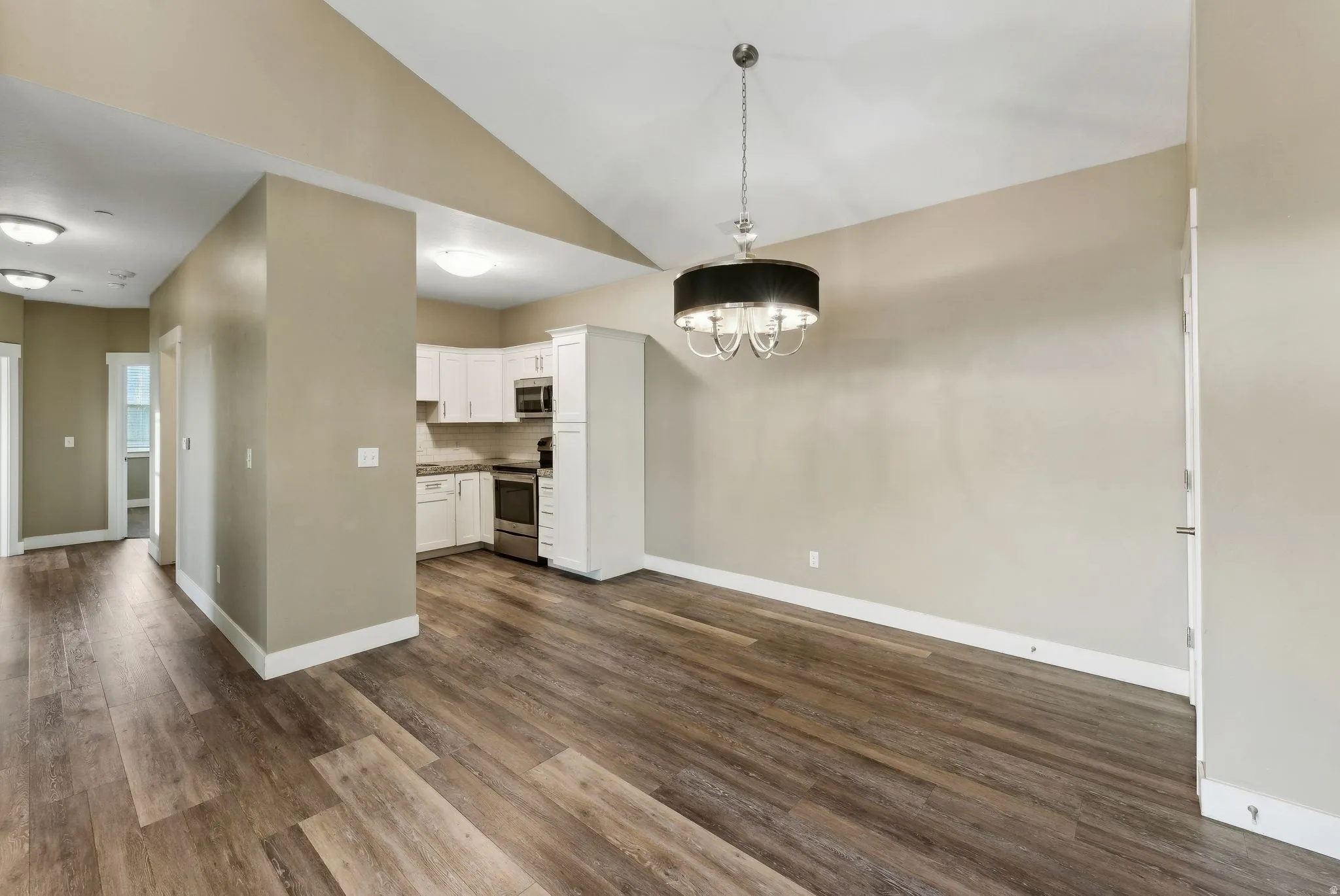 Unfurnished dining area with lofted ceiling, dark wood-type flooring, and suspended lighting