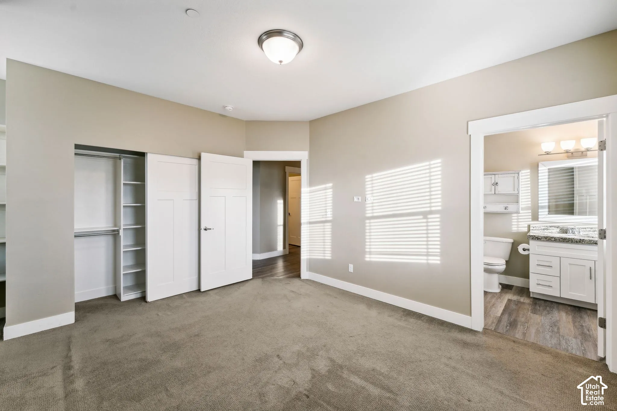 Unfurnished bedroom with a closet, dark colored carpet, and ensuite bathroom