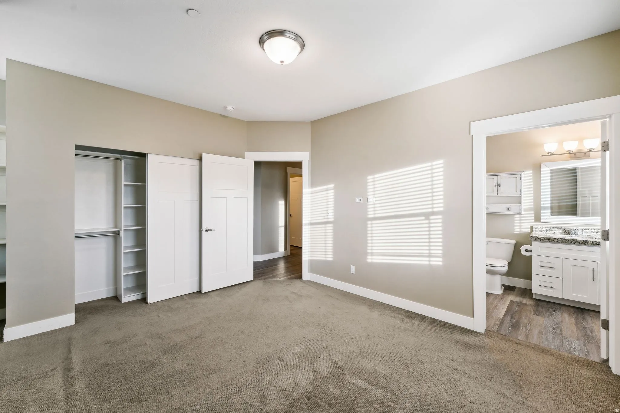 Unfurnished bedroom with a closet, dark colored carpet, and ensuite bathroom