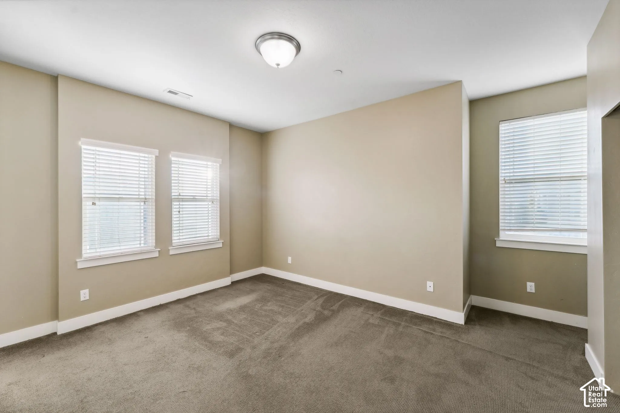 Spare room featuring dark colored carpet and baseboards