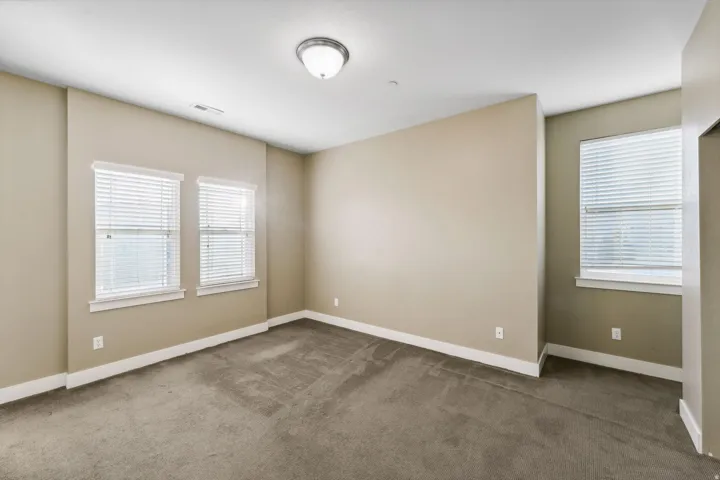 Spare room featuring dark colored carpet and baseboards