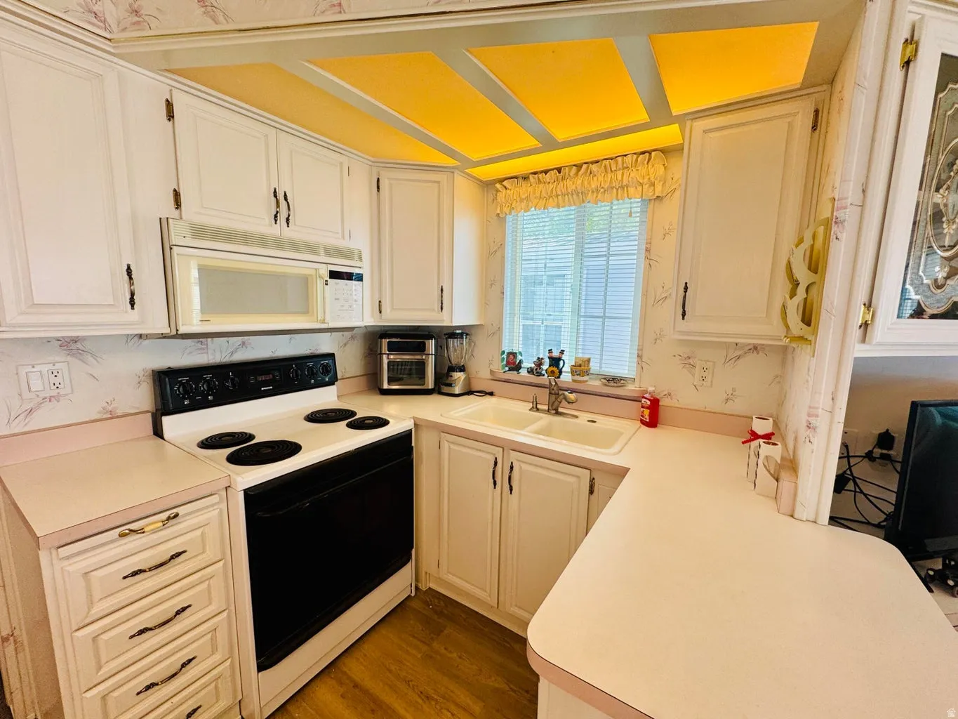 Kitchen featuring range with electric stovetop, light countertops, white microwave, wallpapered walls, and dark wood-type flooring