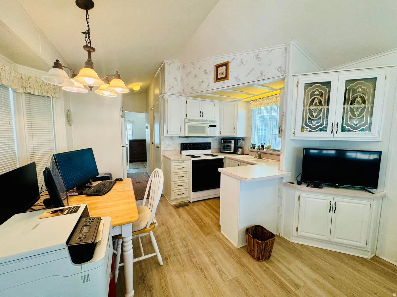 Kitchen featuring light countertops, white appliances, white cabinetry, light wood-style flooring, and a peninsula
