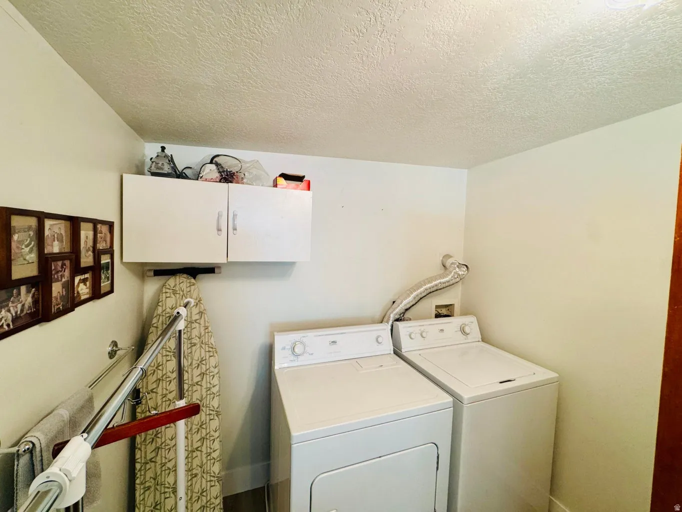 Laundry room featuring cabinet space, independent washer and dryer, and a textured ceiling