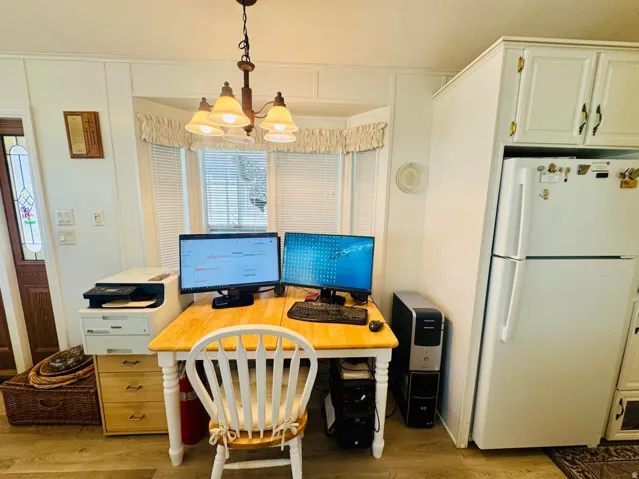 Office area with light wood-style floors, crown molding, and suspended lighting