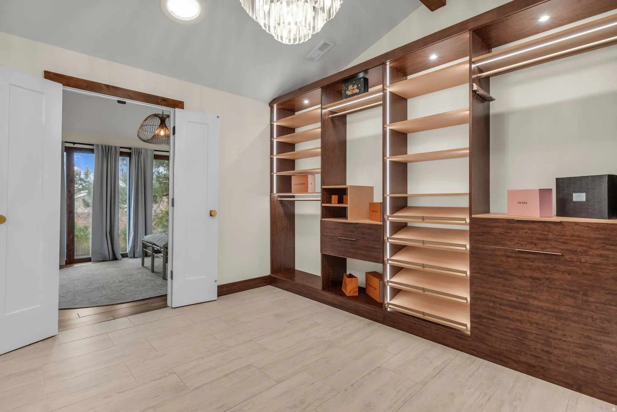 Walk in closet featuring lofted ceiling, light wood-style floors, and hanging lights