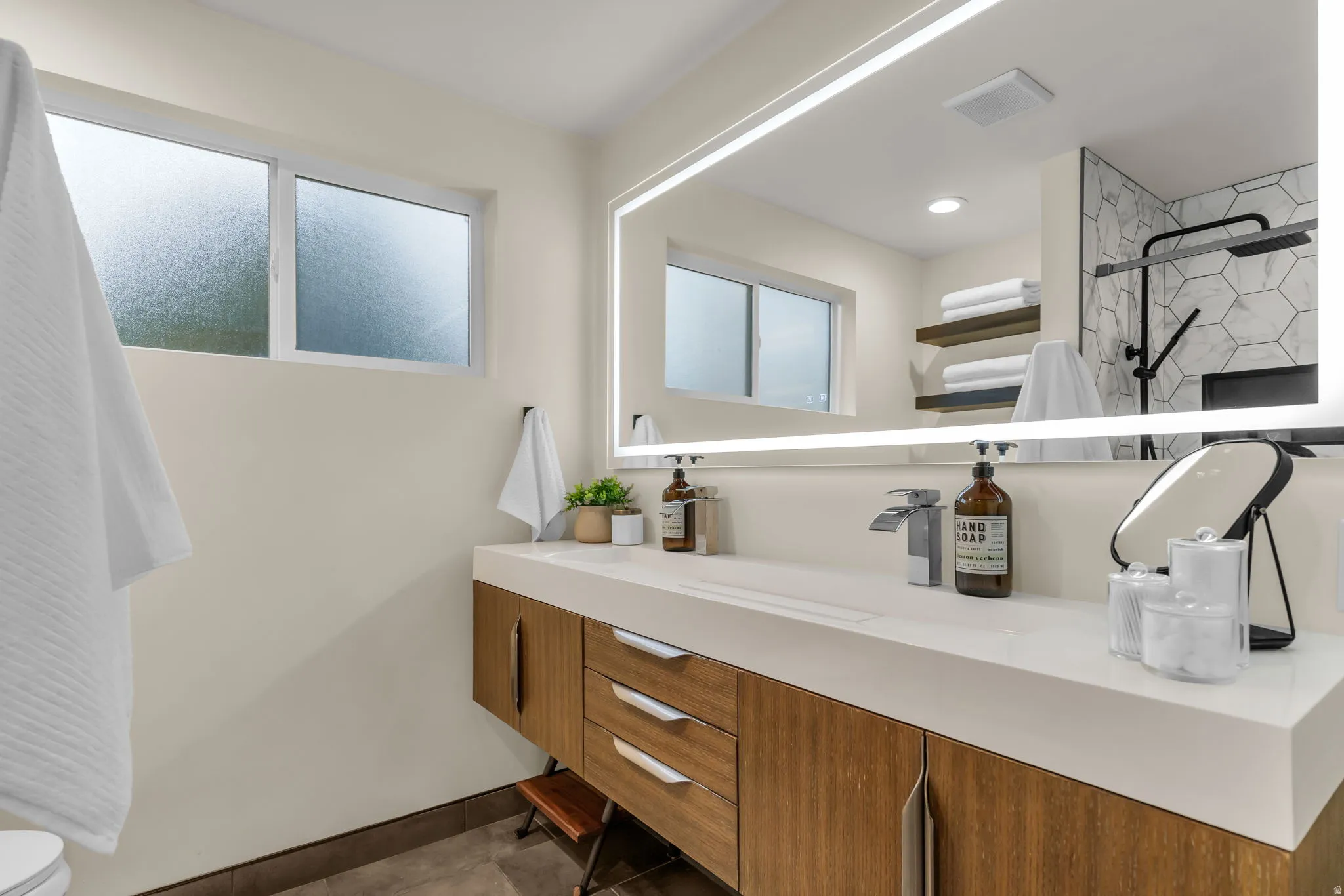 Full bathroom with vanity, dark tile patterned flooring, and a shower