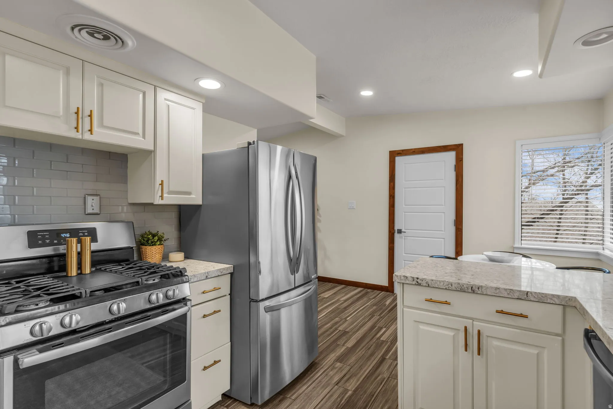 Kitchen with stainless steel appliances, white cabinetry, recessed lighting, dark wood finished floors, and light stone counters