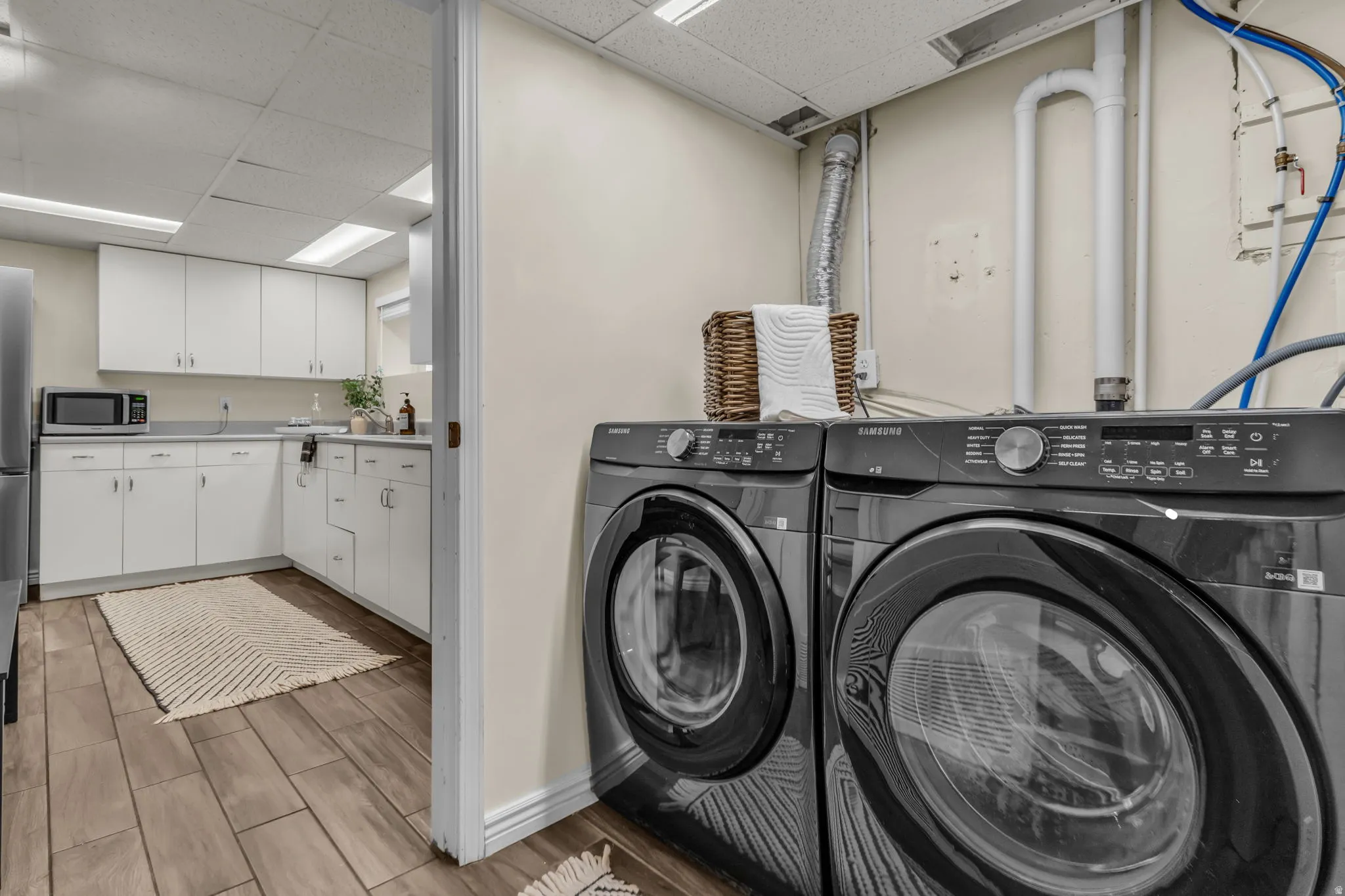 Laundry area with a drop ceiling, wood tiled floors, and independent washer and dryer