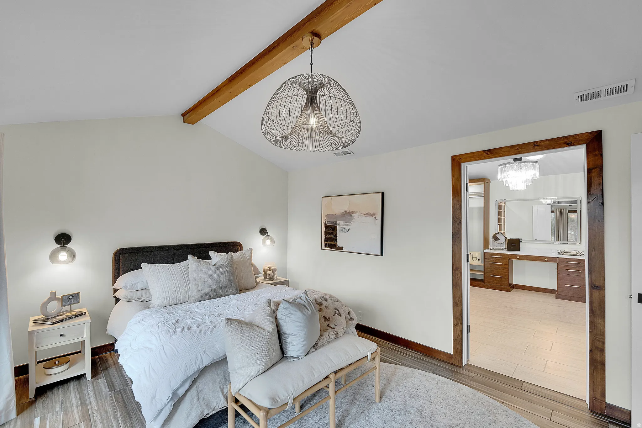 Bedroom featuring a chandelier, wood finished floors, beamed ceiling, and connected bathroom