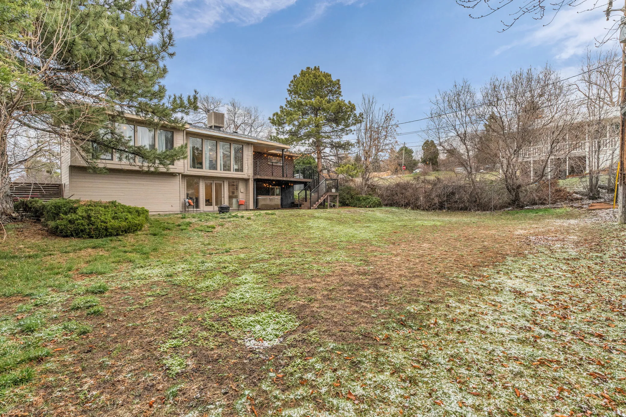 View of grassy yard with a wooden deck and a patio area