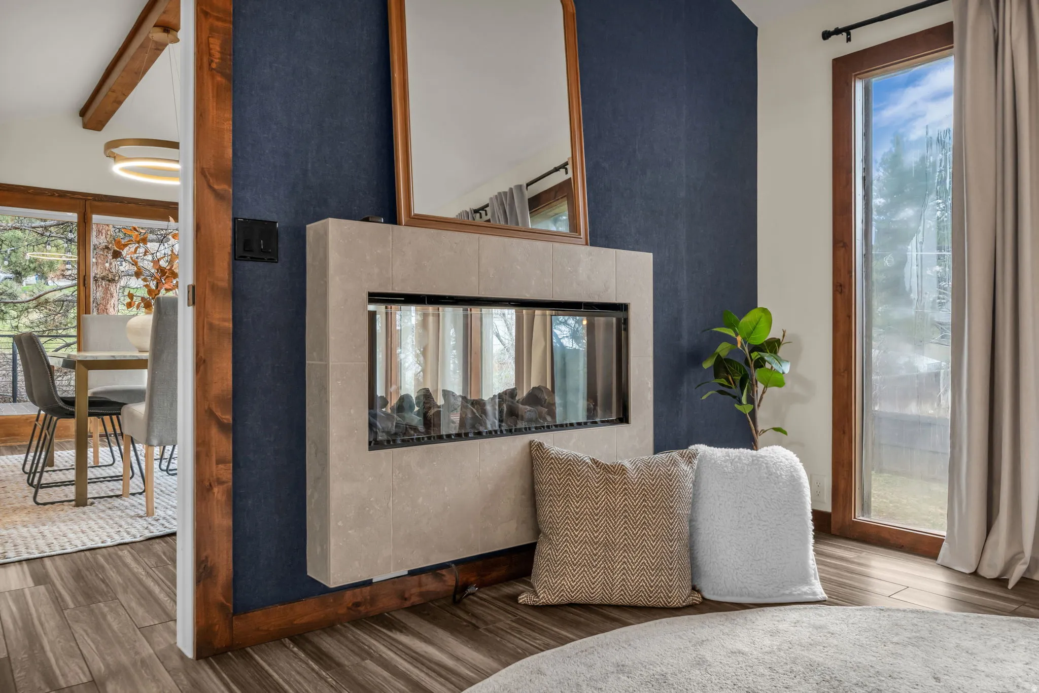 Sitting room featuring wood finished floors, healthy amount of natural light, a multi sided fireplace, and lofted ceiling with beams