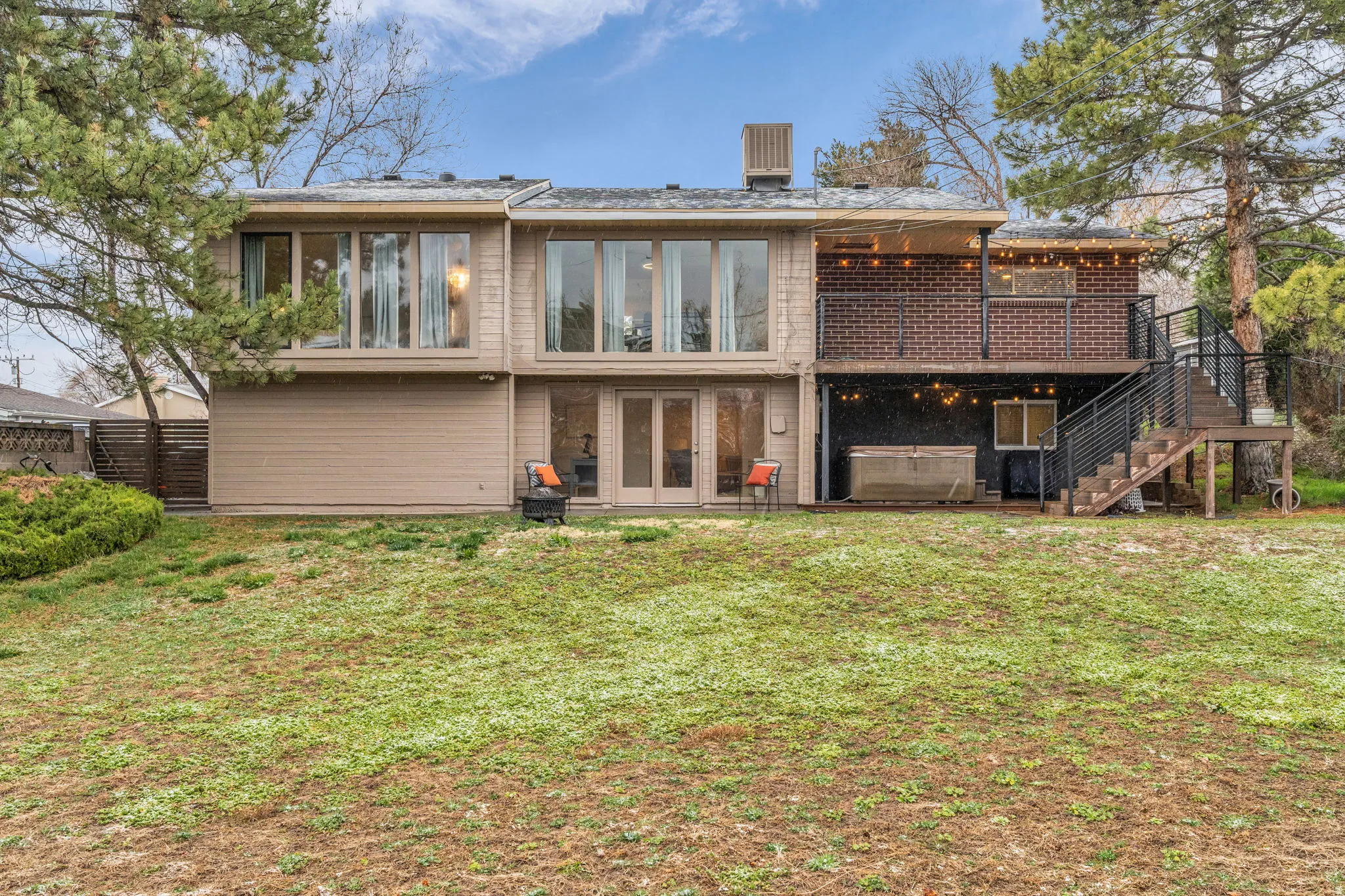Rear view of property with a hot tub, a patio area, a wooden deck, french doors, and brick siding
