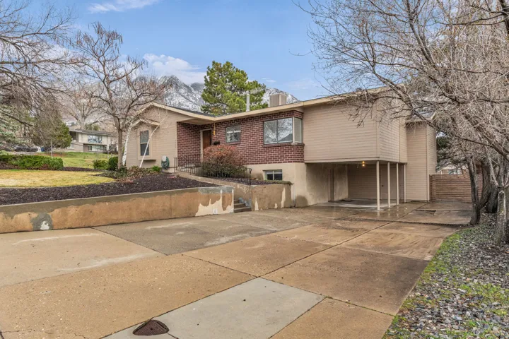View of front of property with concrete driveway, brick siding, and a chimney