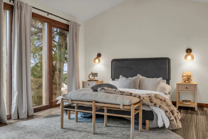 Bedroom featuring vaulted ceiling, wood finished floors, and multiple windows