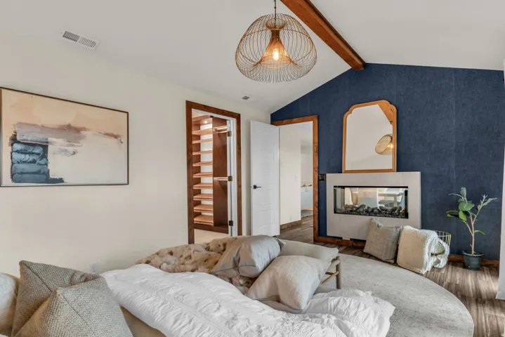Living area with beamed ceiling, a multi sided fireplace, and wood finished floors