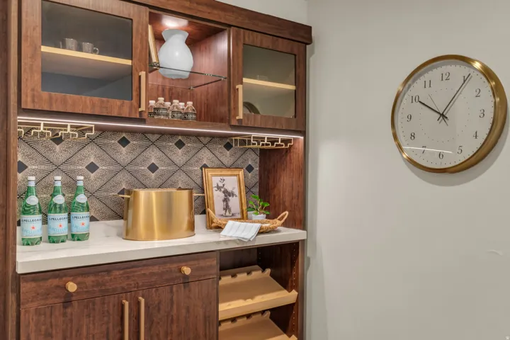 Bar area with light countertops, glass fronted cabinets, tasteful backsplash, and dark wood finish cabinets