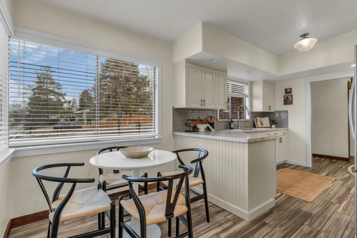 Kitchen with a peninsula, light countertops, light wood-type flooring, decorative backsplash, and white cabinets