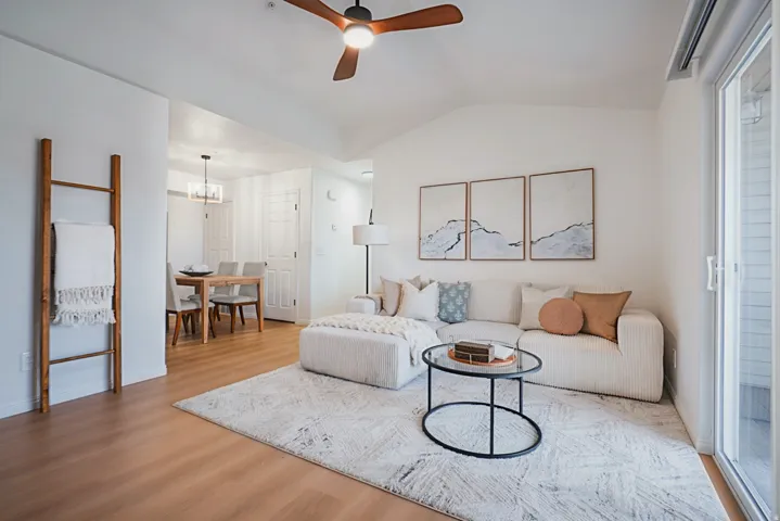 Living area featuring a ceiling fan, lofted ceiling, and light wood-type flooring