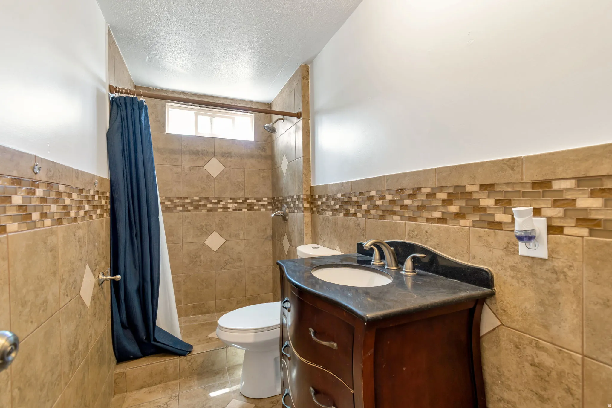 Bathroom with vanity, a shower stall, tile walls, wainscoting, and light tile patterned floors