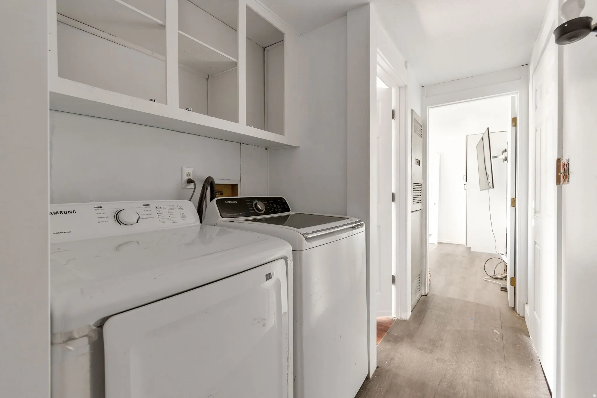 Laundry area featuring light wood-style flooring, washer and clothes dryer, and a heating unit