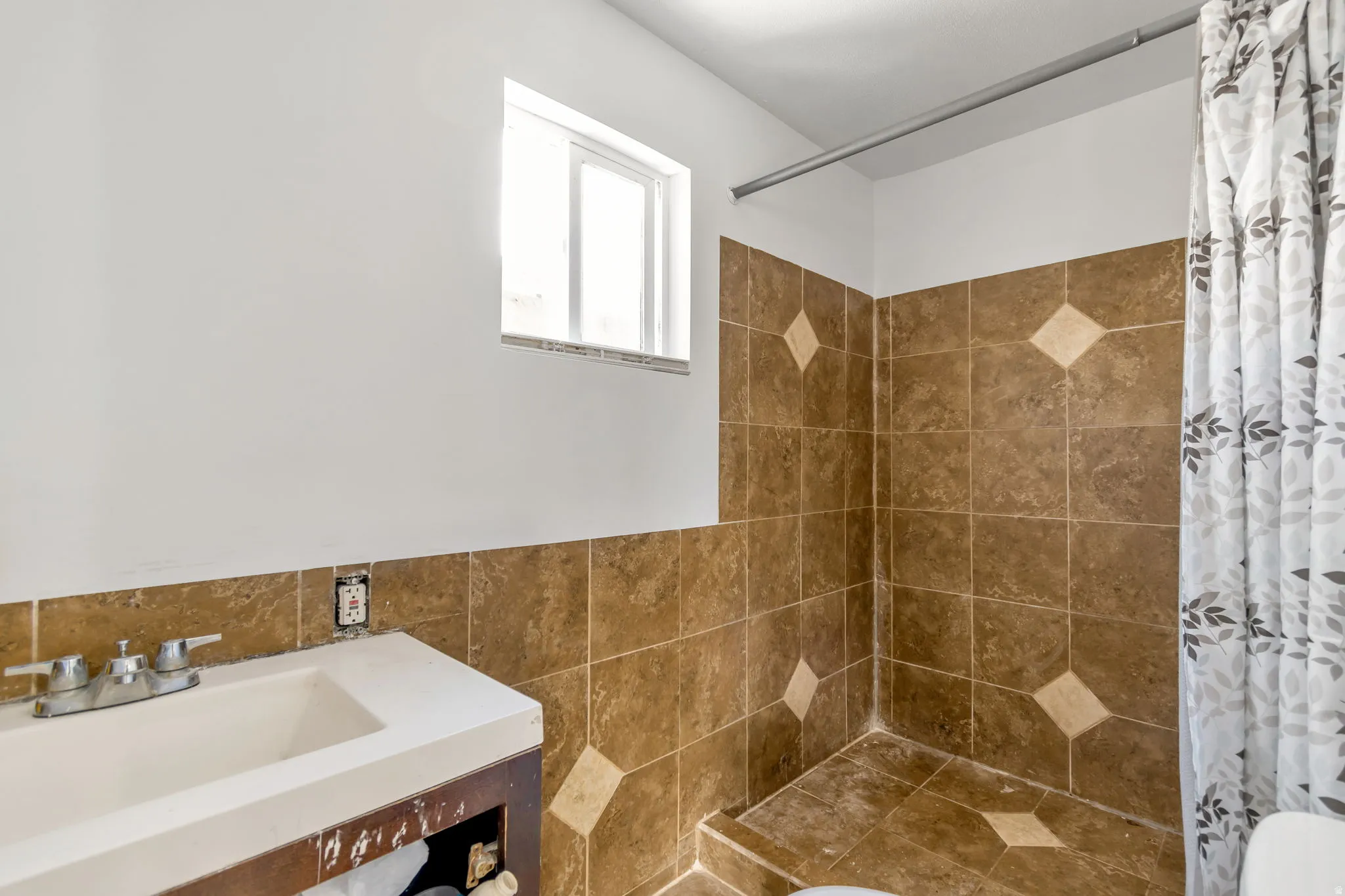Bathroom featuring a tile shower, tile walls, and vanity