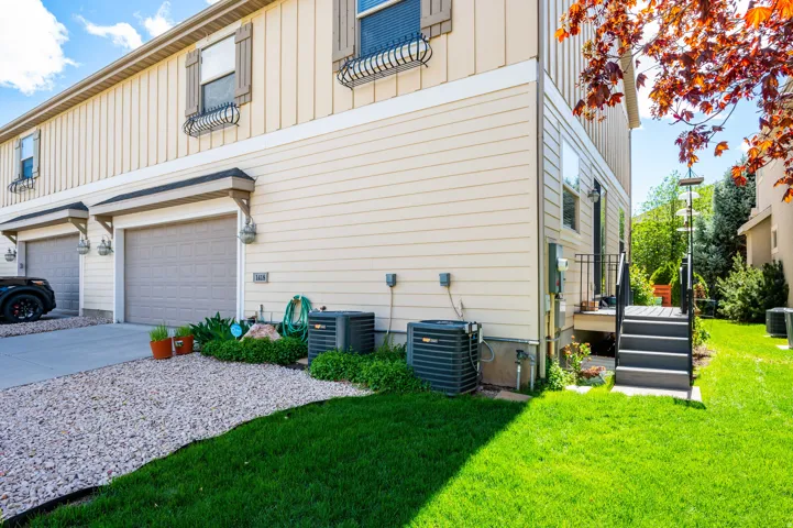 View of side of home with board and batten siding, an attached garage, concrete driveway, and a yard