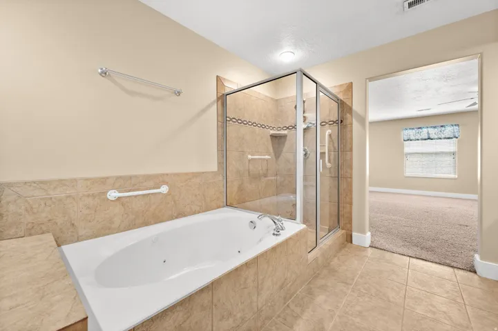 Full bathroom featuring a shower stall, light tile patterned floors, a tub with jets, and light carpet