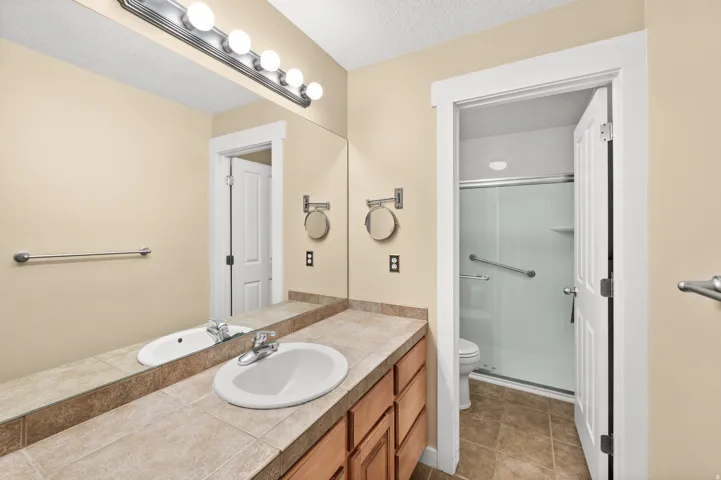 Full bath featuring a stall shower, vanity, a textured ceiling, and light tile patterned flooring