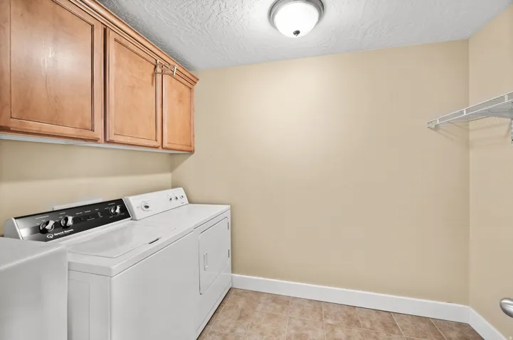 Laundry area featuring a textured ceiling, washing machine and dryer, and cabinet space