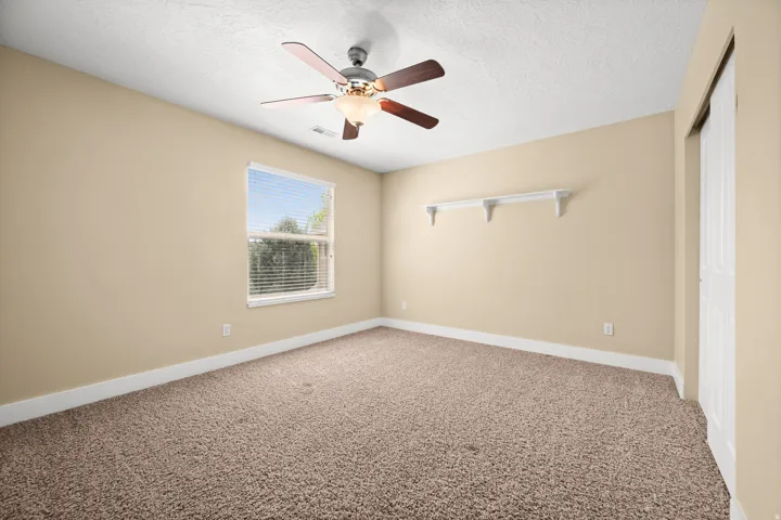 Unfurnished room featuring light colored carpet, ceiling fan, and a textured ceiling