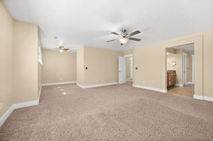 Empty room with a ceiling fan, light carpet, and a textured ceiling