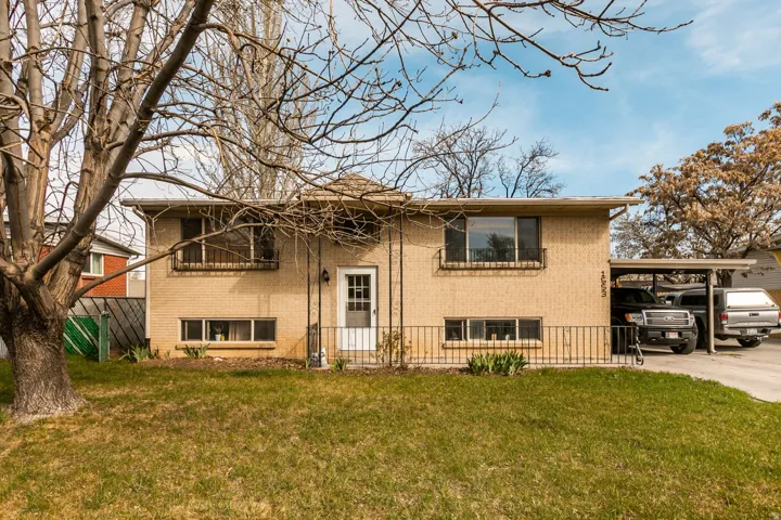 Bi-level home with brick siding, a front yard, and an attached carport