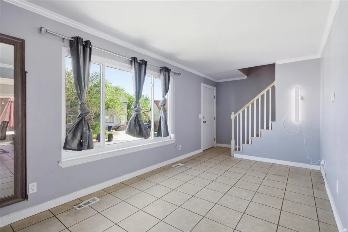 Empty room featuring crown molding and light tile patterned flooring