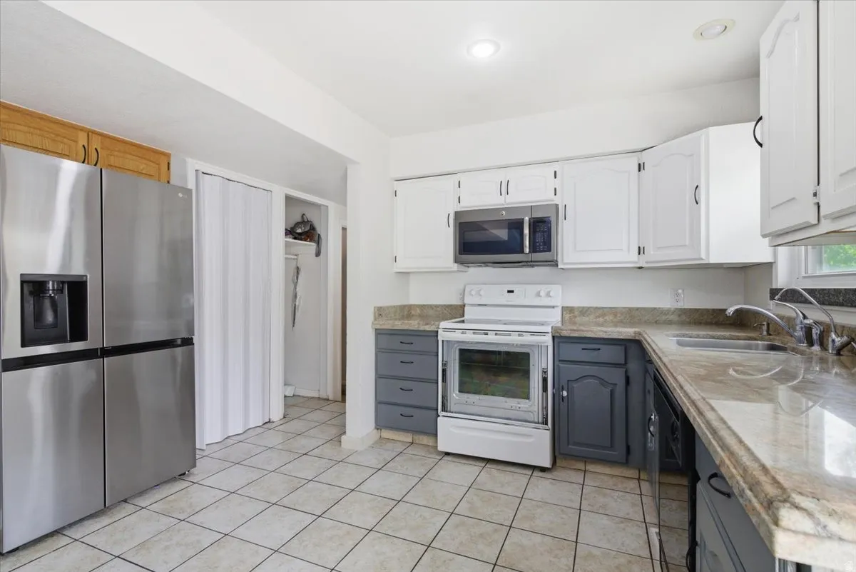 Two tone kitchen featuring two tone cabinetry, stainless steel appliances, and light tile patterned floors