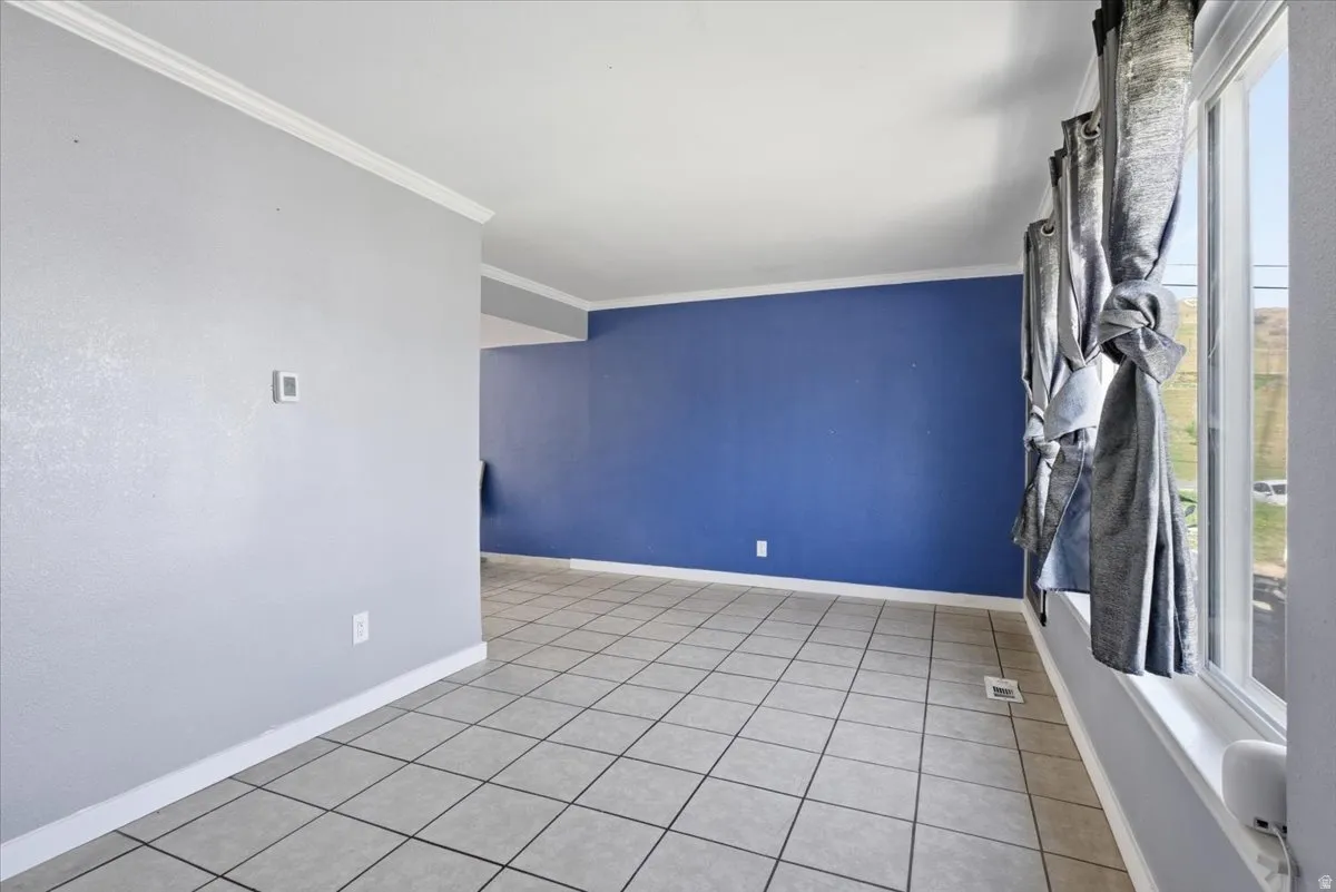 Empty room with ornamental molding and light tile patterned floors