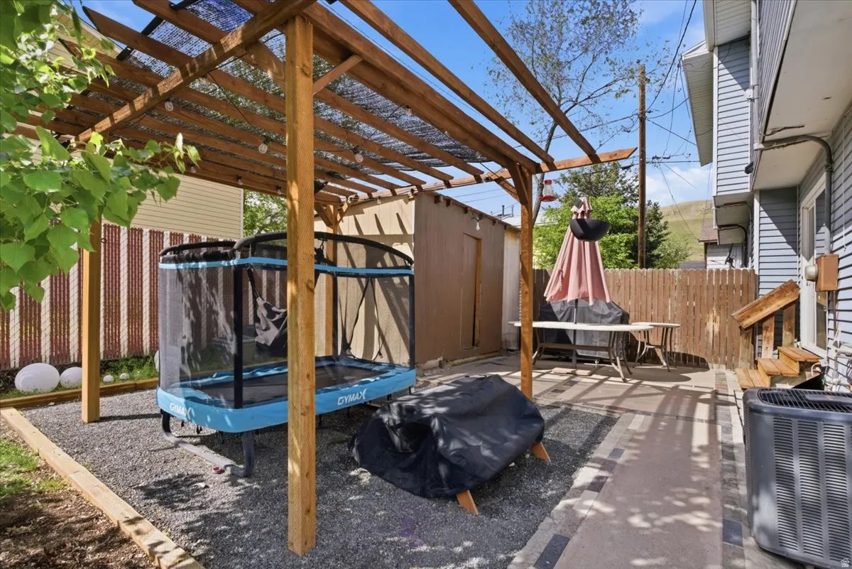 Fenced backyard featuring a trampoline and a patio area