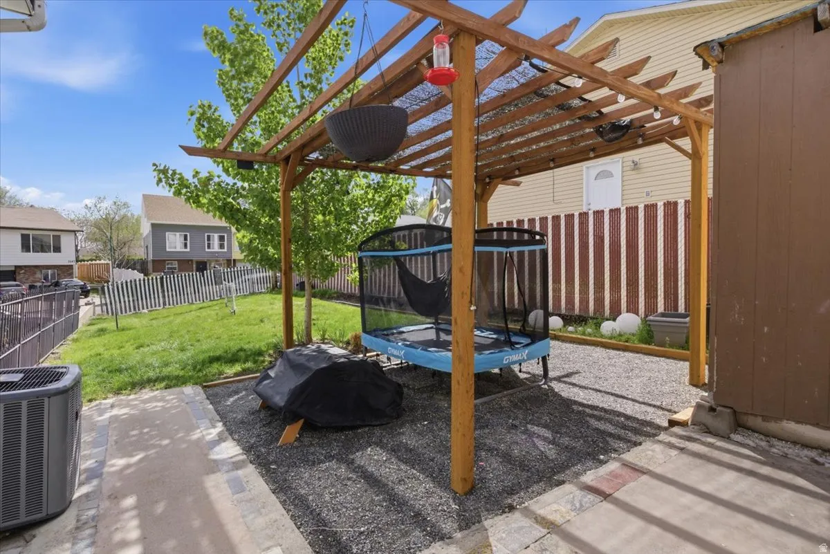 Fenced backyard featuring a trampoline, a patio, and a pergola