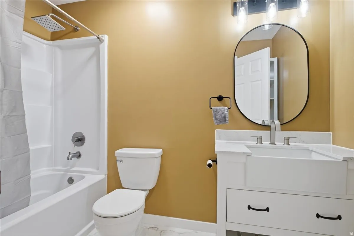 Bathroom featuring vanity, shower / bath combo, and marble look tile flooring