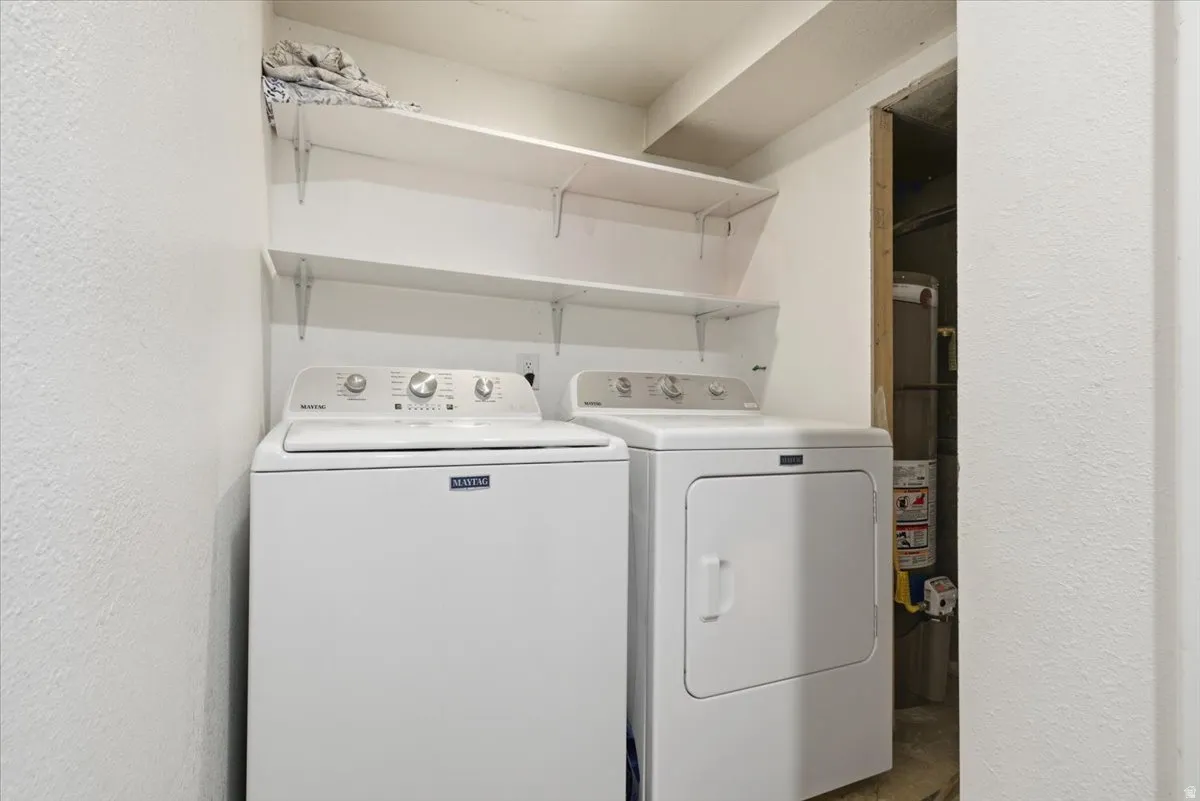 Laundry area featuring a textured wall, independent washer and dryer, and gas water heater