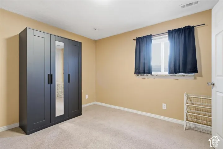 Unfurnished bedroom featuring light carpet and baseboards