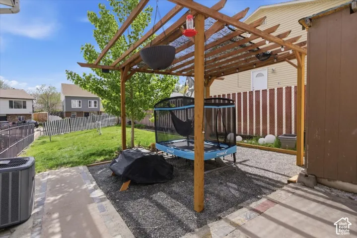 Fenced backyard featuring a trampoline, a patio, and a pergola