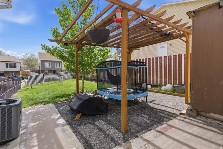Fenced backyard featuring a trampoline, a patio, and a pergola